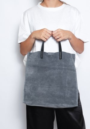Borsa a spalla in suede grigia con manici in pelle nera, caratterizzata da una semplice forma rettangolare e una superficie liscia. Nessun motivo o logo visibile.