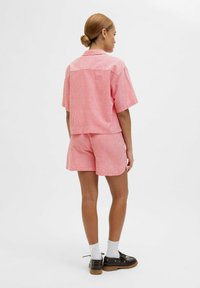 Rood en wit gestreept tshirt met korte mouwen, gecombineerd met bijpassende shorts. De stof lijkt lichtgewicht en heeft een lichte textuur.