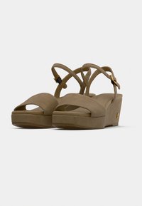 Μπεζ πλατφόρμες πέδιλα από σουέντ με σταυρωτά λουράκια και ανοιχτή μύτη. Διαθέτουν χρυσή αγκράφα και παχύ, μαξιλαρωτό πάτο.