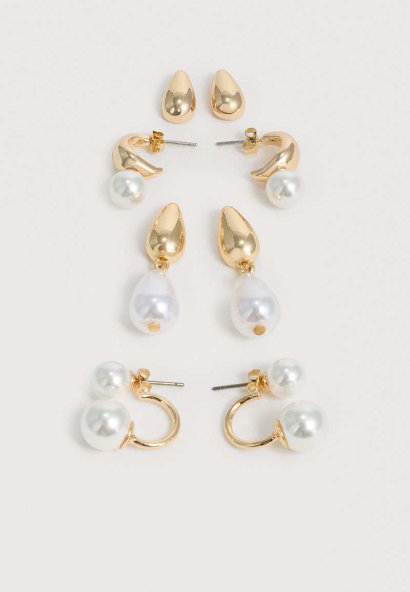 Τέσσερα ζεύγη χρυσών και μαργαριταρένιων σκουλαρικιών τοποθετημένα κάθετα σε λευκό φόντο, κάθε ζεύγος με μοναδικά σχήματα και μαργαριταρένιες λεπτομέρειες.