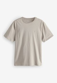 Beige kokvilnas T-krekls ar īsām piedurknēm, apaļu dekoltē un mazu logo kreisajā pusē. Gluda tekstūra bez redzamām rakstām.