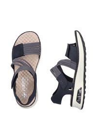 Sandales bleu marine avec semelle texturée beige, sangles élastiques tissées et matériel ajustable. Semelle en caoutchouc noir épais avec amorti d'air.