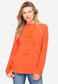 Feloranje langemouwen shirt met een relaxte pasvorm en een subtiele grafiek van een karakter. Zachte textuur, ronde halslijn en verlaagde schouders.