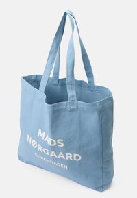 Jasnoniebieska bawełniana torba na ramię z dwoma solidnymi uchwytami oraz białym napisem "MADS NØRGAARD COPENHAGEN" z jednej strony. Prosty design.