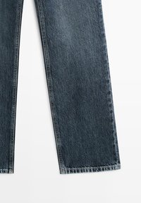 Blau-Jeans mit geradem Bein, sichtbaren Nahtstichen und umgeschlagenen Säumen vor weißem Hintergrund.
