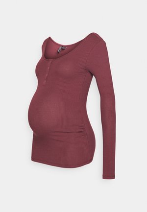 Chemise de maternité bordeaux à manches longues et à côtes, avec encolure dégagée et patte de boutonnage sur fond blanc.