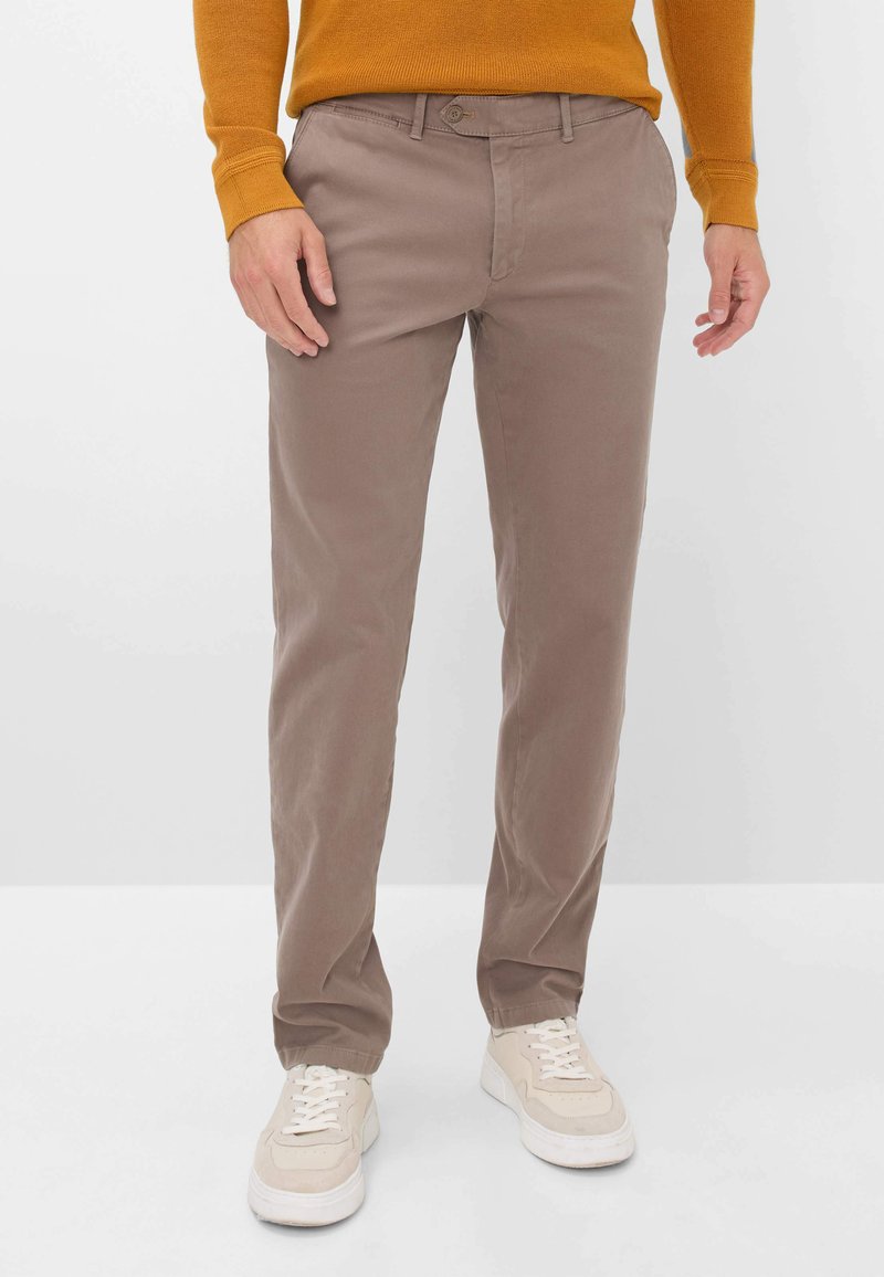 Pantalons en coton marron clair avec une coupe droite, dotés d'une fermeture à bouton, de poches latérales et d'une texture lisse, associés à des baskets beiges.