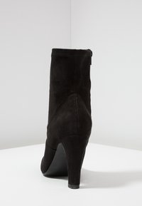 Bottine en daim noir avec talon effilé et fermeture éclair à l'arrière. Caractérisée par une texture lisse et un design minimaliste.