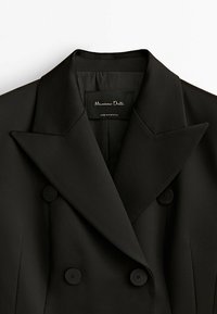 Blazer noir croisé avec larges revers, quatre boutons noirs et étiquette intérieure indiquant « Massimo Dutti, Made in Portugal. »