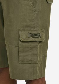 Olive green cargo shorts made of cotton, featuring a side pocket and embroidered "Lonsdale London" logo. Smooth texture with visible stitching.