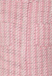 Un tissu tissé rose et blanc a une surface texturée avec des accents noirs. Il dispose de deux poches avant et présente un design structuré.