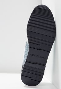 Semelle de chaussure en matériau caoutchouté, avec une surface texturée à rainures horizontales et un panneau latéral à motifs bleus et gris. Nom de la marque embossé.