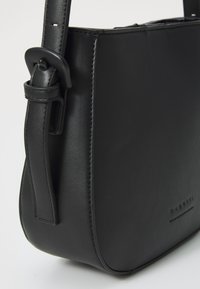 Borsa a spalla in pelle nera con texture liscia, forma rettangolare, tracolla regolabile e logo impresso in modo discreto.