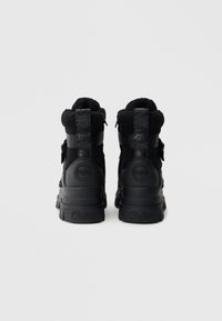 Fekete magas szárú sportcipők, texturált felsőrésszel, párnázott szegéllyel és kontrasztos gumi talppal, dombornyomott logóval.