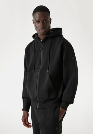 Schwarzer Kapuzenpullover aus weichem Stoff, mit einem Frontreißverschluss, Kordelzügen, Kängurutasche und gerippten Bündchen.