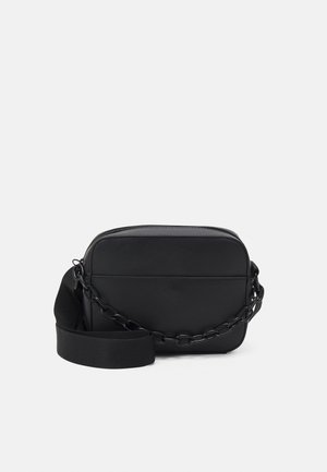 Zwarte rechthoekige crossbody tas gemaakt van soepel materiaal, met een metalen kettingband en een nylon riem. Ritssluiting aan de bovenkant.