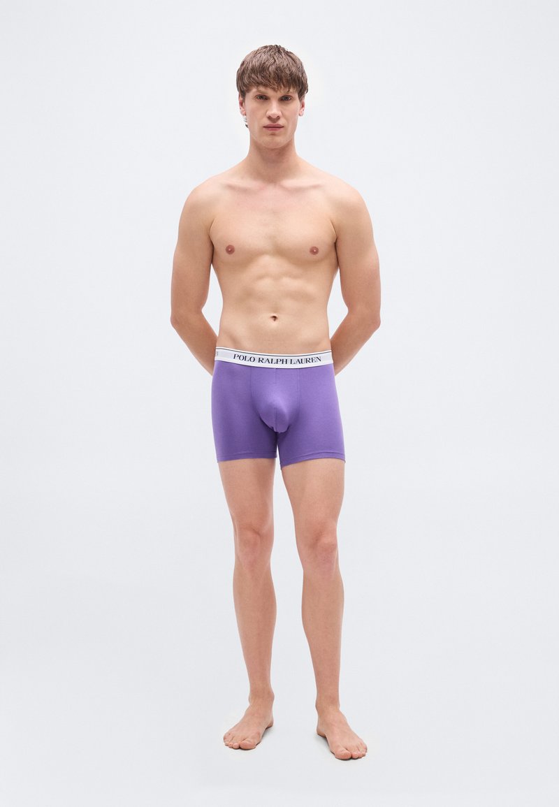 Μωβ βαμβακερό μπόξερ με άσπρη ελασ τική μέση που φέρει το λογότυπο «POLO RALPH LAUREN», εμφανιζόμενο σε μοντέλο με γυμνό στήθος.