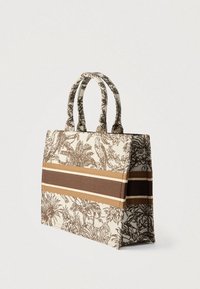 Vászon szalagos táska barna és krémszínű növényi mintával, két felső fogóval és barna és bézs vízszintes csíkos díszítéssel.