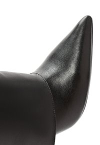 Scarpa nera in pelle con punta affusolata, caratterizzata da una texture liscia e un design aderente alla caviglia. Il tacco è alto e elegantemente affilato.