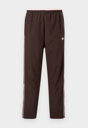 Smeđe trenirka hlače s elastičnim pojasom, s ružičastim detaljima i bijelim bočnim prugama. Izrađene od glatkog, laganog materijala.