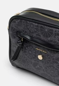 Musta nahkalaukku, jossa on geometrinen kuvio, kultaiset yksityiskohdat, ylhäältä avattava vetoketju ja etutasku, jossa on nahkayangin koriste.