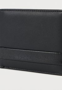 Μαύρο δερμάτινο πορτοφόλι με απαλό υφή, με λεπτό σχεδιασμό και οριζόντια λωρίδα στο κέντρο. Μινιμαλιστική ραφή.