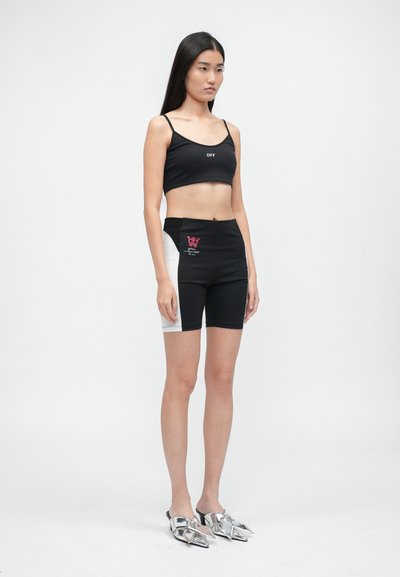Černý crop top s logem "OFF", spárovaný s černými šortkami s vysokým pasem a bílým bočním panelem s růžovou grafikou. Stříbrné boty.