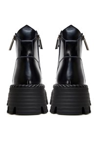 Stivaletti neri in pelle con suola spessa e dentellata, punta appuntita e dettagli con zip sul tallone. Finitura lucida con dettagli a corda.