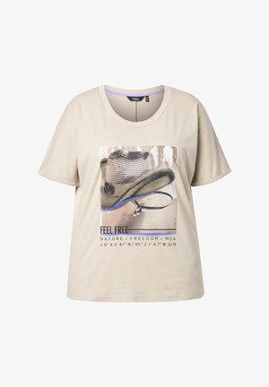 Beżowa koszulka z krótkim rękawem z grafiką kapelusza kowbojskiego i tekstem "CZUJ SIĘ WOLNY W PRZYRODZIE / WOLNOŚĆ / JA I" oraz współrzędnymi geograficznymi.