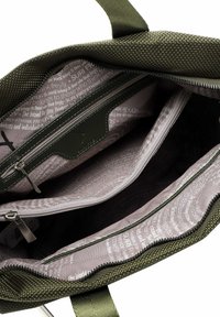 Borsa a tote verde oliva con esterno testurizzato, dotata di chiusura con zip, molteplici scomparti interni e fodera a motivo grigio chiaro.