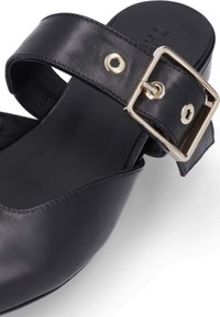 Schwarze Lederschlappen mit einem breiten Riemen und einem goldenen Schnallenakzent. Glatte Textur mit einem runden Zehendesign und minimalen Nähdetails.