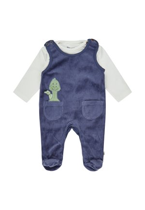 Marineblaue Corduroy-Latzhose mit zwei Taschen, die auf der Vorderseite eine grüne Dinosaurier-Stickerei aufweist. Darunter ein langärmliges weißes Hemd.