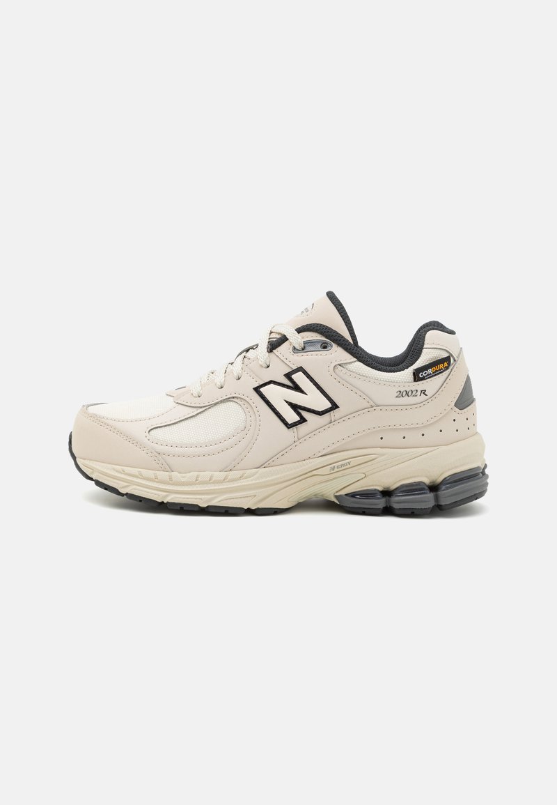Beige Laufschuh mit Obermaterial aus Mesh und Synthetik, schwarzen Akzenten, gepolstertem Kragen und dämpfender Sohle. Mit "2002R"-Logo und Haltbarkeitsschild.