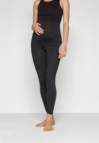 Leggings de maternité noirs avec une taille haute, une texture lisse et une coupe ajustée, adaptées pour un port confortable pendant la grossesse.