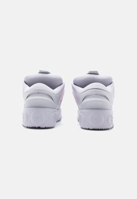 Pár bílých a růžových sportovních bot zobrazených zezadu, s polstrovanými límci a vyraženými oblíbenými vzory na podrážkách.