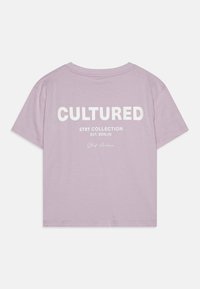 Īsām piedurknēm, lilac krāsas T-krekls ar lieliem baltiem burtiem uz aizmugures, kas lasāmi "CULTURED", zem tā rakstīts "STRt COLLECTION EST. BERLIN".