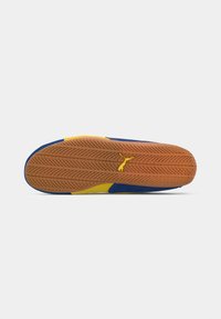 Schoen met een gestructureerde rubberen zool in oranje met een zigzagpatroon; bovenkant in blauwe en gele suede, met een flexibele vormgeving voor grip.