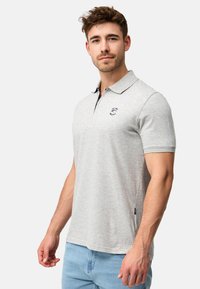 Grå polo-t-shirt i blødt, struktureret stof med krave, korte ærmer og et lille broderet logo på brystet.