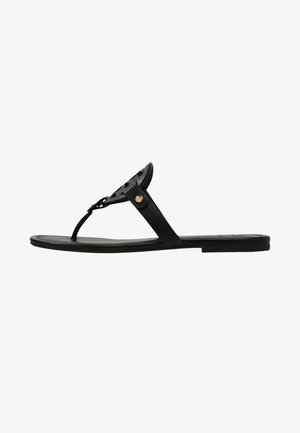 Chinelo preto feito de material suave, apresentando uma tira estreita no dedo do pé e um design de recortes decorativo, acentuado com um detalhe em botão dourado.