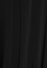 Tejido de vestido negro con una textura suave, que presenta un diseño drapeado y costuras verticales. La luz se refleja sutilmente, realzando la profundidad.