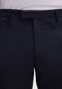 Pantaloni blu navy realizzati in tessuto strutturato, con fronte piatto, passanti per la cintura e una vita liscia senza tasche.