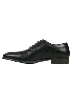 Chaussure habillée en cuir noir avec un bout pointu, cinq œillets pour les lacets, un discret détail de couture et un petit talon empilé.