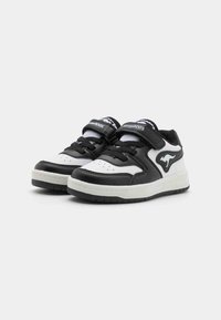 Svarte og hvite sneakers med overdel i lær og mesh, med borrelås, teksturert såle og fremtredende logo-detalj.