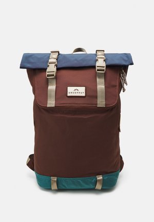 Plecak z klapą zwijaną, brązowym korpusem, turkusowym spodem, niebieską górną klapą, beżowymi paskami i przednią naszywką z napisem Doughnut.