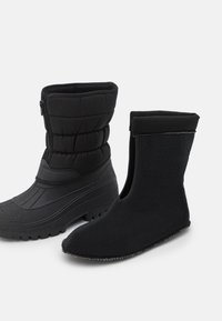 Un par de botas de invierno negras aislantes con suelas de goma gruesa y un forro interior de felpa extraíble.