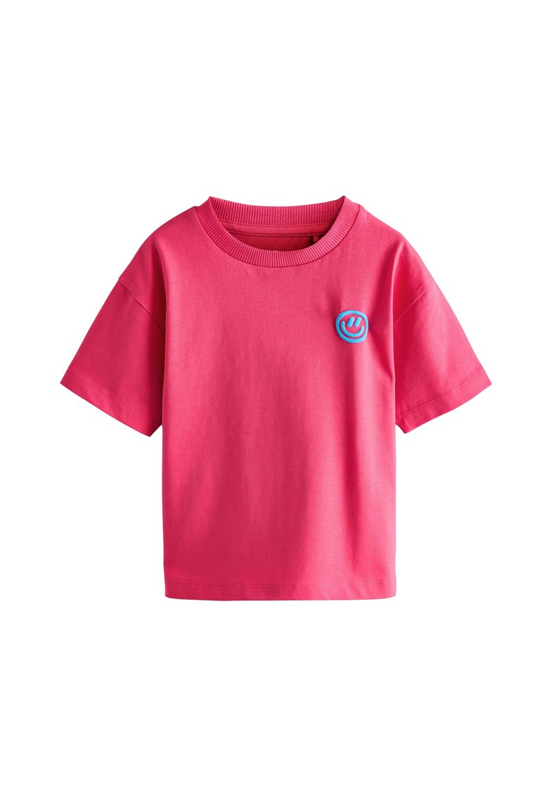 Lyserød bomulds-t-shirt med rund hals og korte ærmer. Har en blå cirkulær smiley-logo på forsiden. Glat tekstur, afslappet design.