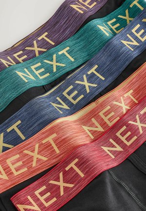 Monipakkaus joustavyöistä eri väreissä: violetti, teal, sininen, punainen ja oranssi, joissa kaikissa on teksti "NEXT" kullalla.