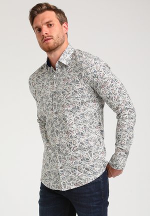 Camisa de botones con estampado en tejido ligero, que presenta un diseño floral en colores suaves sobre un fondo blanco. Manga larga, cuello estándar.