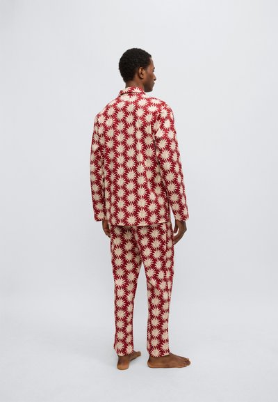 Set de pijamale pentru bărbați, confecționat dintr-un material roșu cu model crem în formă de explozie stelară. Include bluză cu mâneci lungi și pantaloni asortați. Textură moale, croială lejeră.