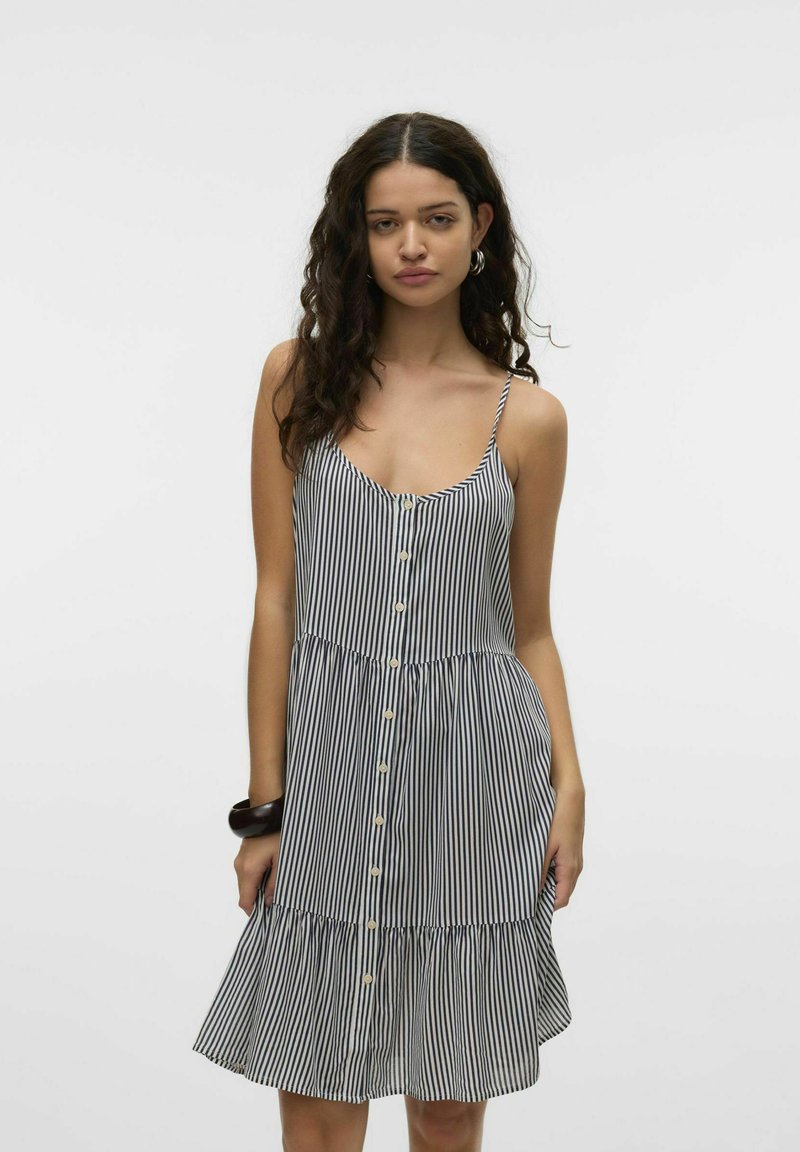 Sukienka bez rękawów w pionowe paski, dopasowana w talii, z rozkloszowanym falbanistym dołem i zapięciem na guziki z przodu. Kolory: granatowy i biały.